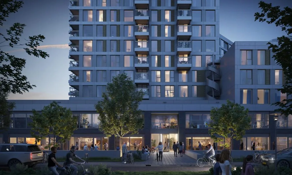 Moderne woontoren aan de H.J.E. Wenckebachweg in de schemering met verlichte ramen, terrassen en mensen op straat.