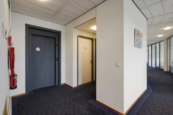 Binnenhal van een kantoorgebouw aan de Laan van S-Gravenmade met een lift, een deur en een gang met glazen kantoorwanden.