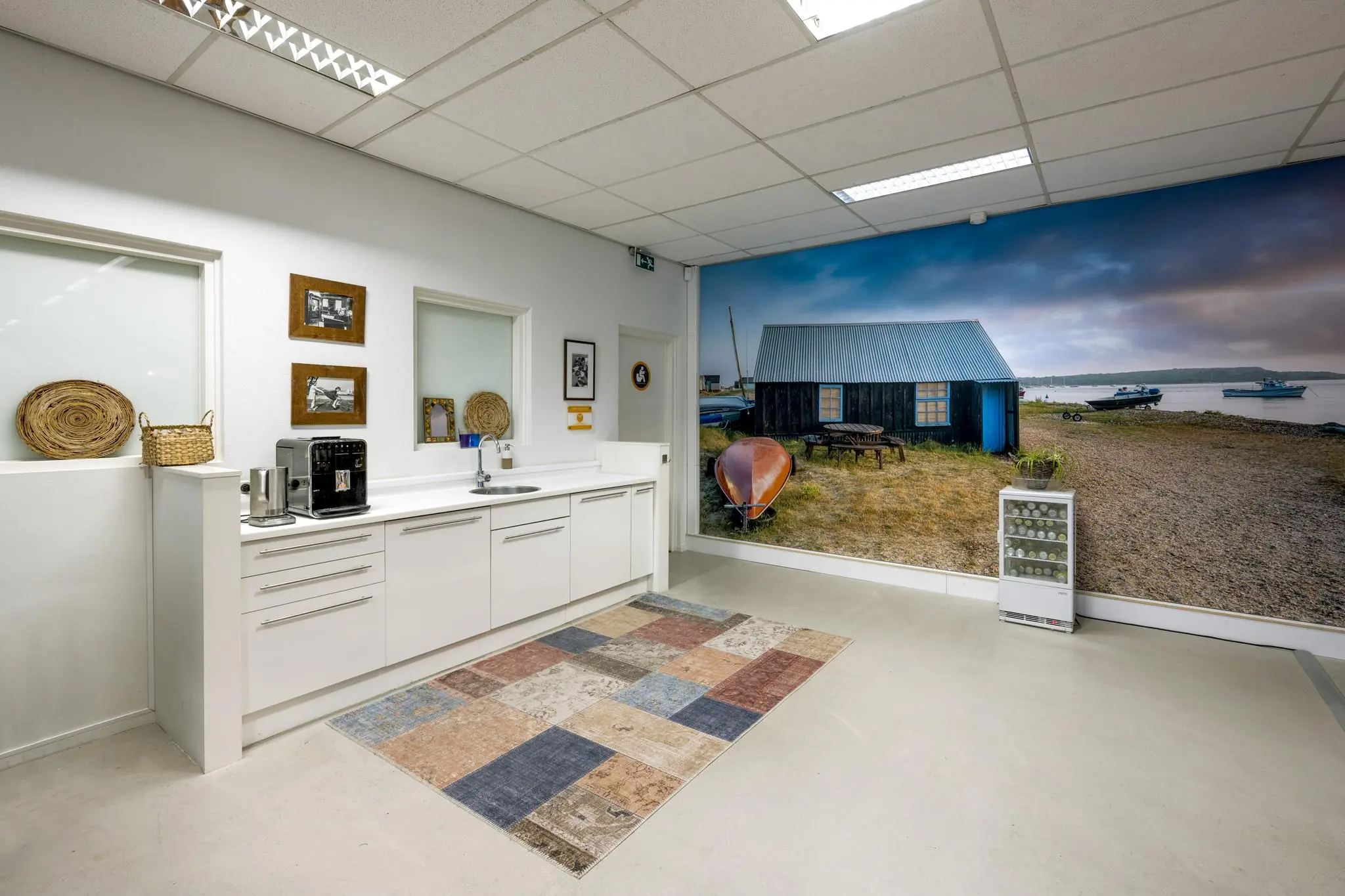 Moderne pantry met witte keuken en fotowand van een vissershut aan het water in Helicopterstraat.