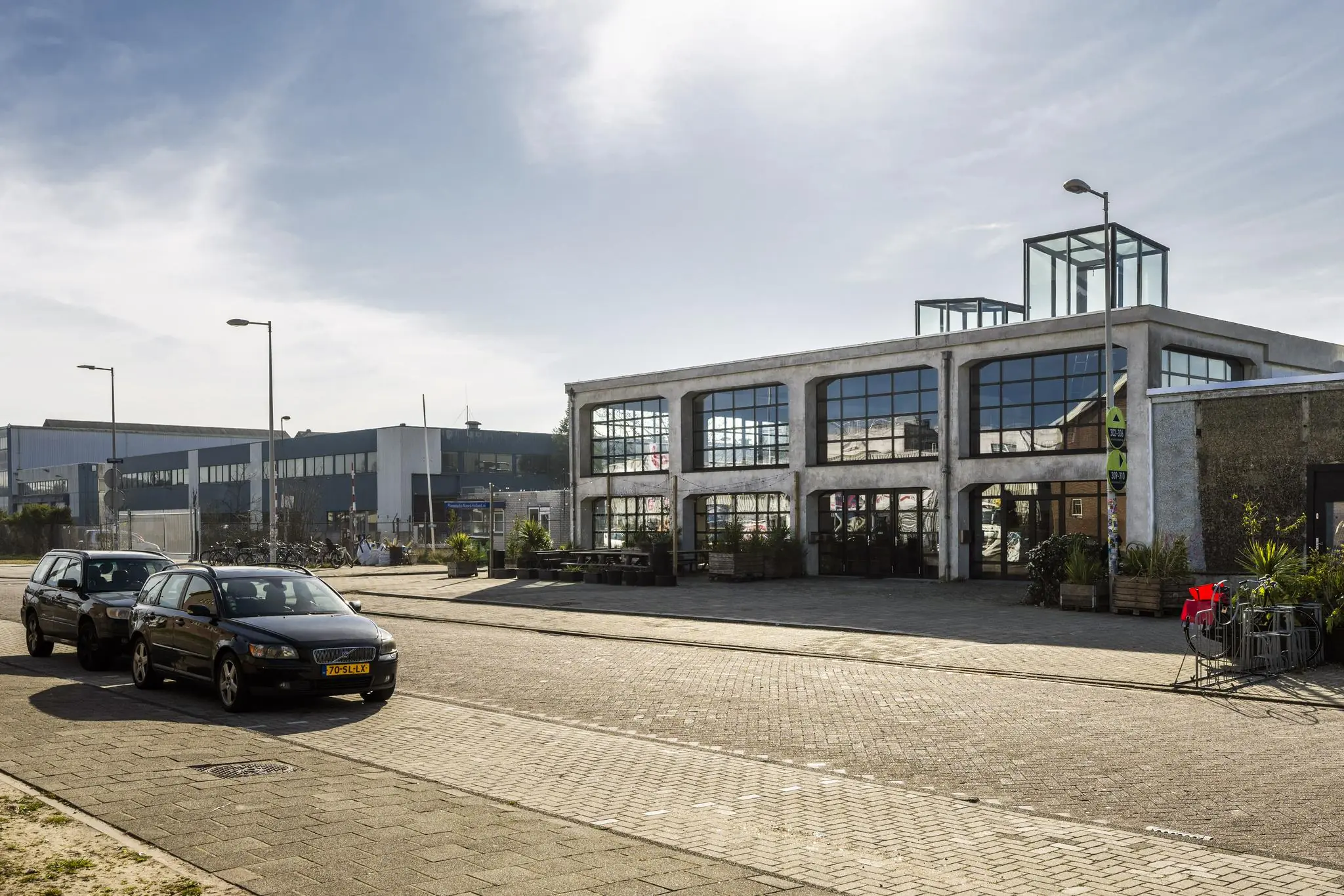 Industrieel pand aan het Gedempt Hamerkanaal met grote ramen en geparkeerde auto's op de voorgrond.