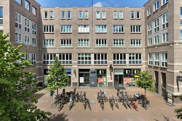 Binnenplein van kantoorgebouw Middenburcht met fietsenstalling en winkels op de begane grond.