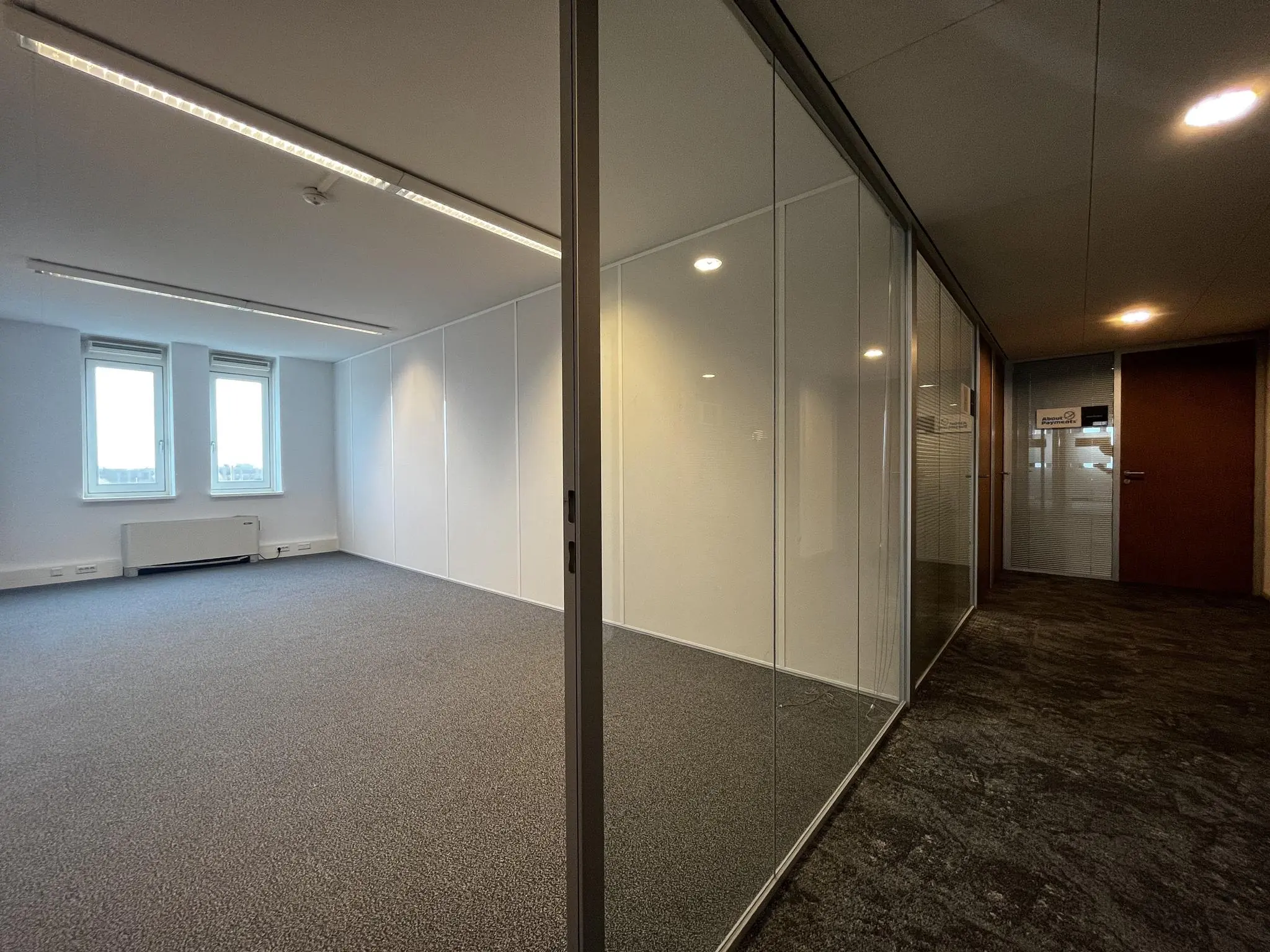 Leeg en licht kantoorpand in gebouw Middenburcht met glazen wanden en tapijtvloer.
