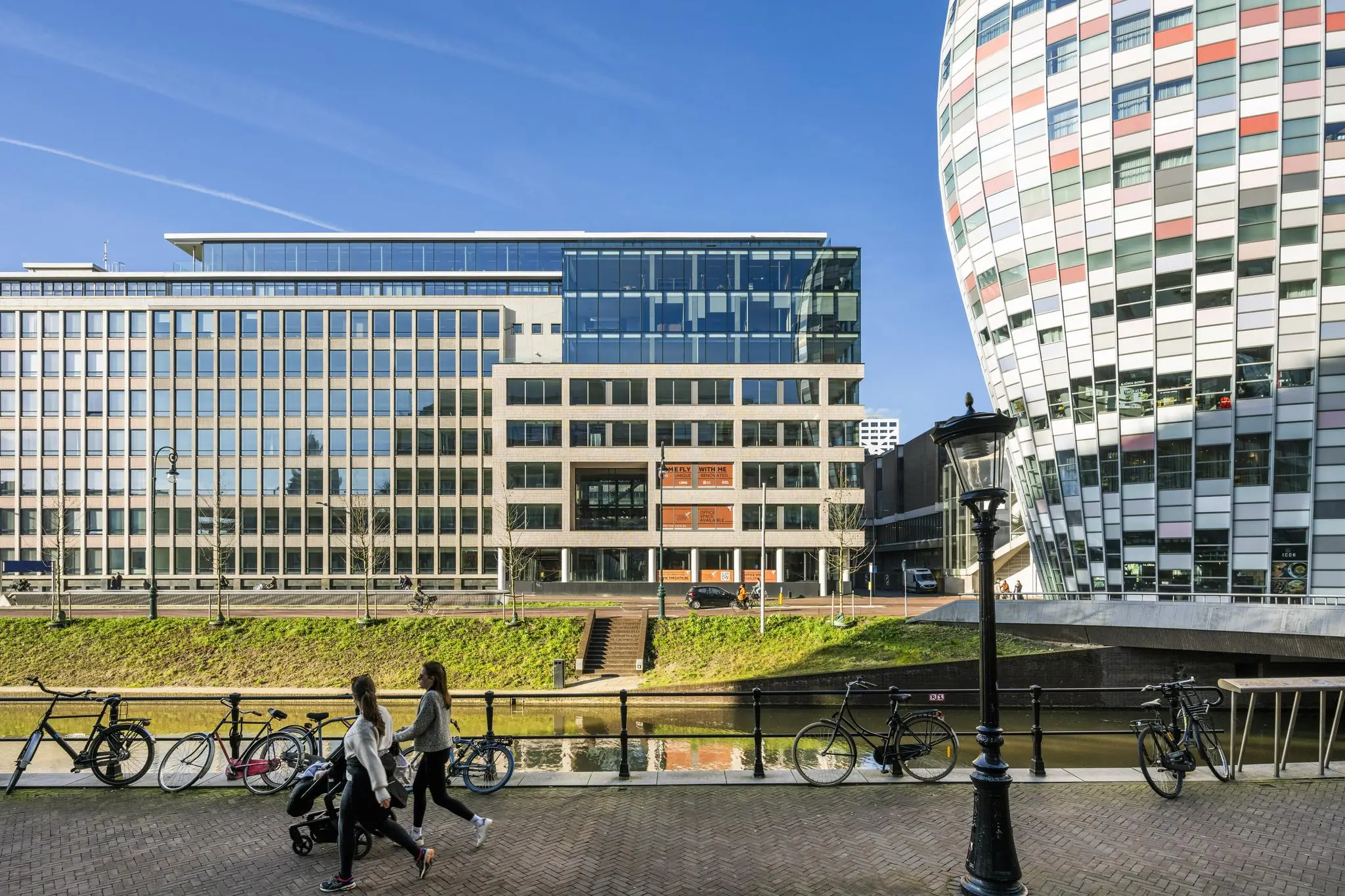Moderne kantoorgebouwen aan de Catharijnesingel in Utrecht met wandelaars, fietsen en een kanaal op de voorgrond.