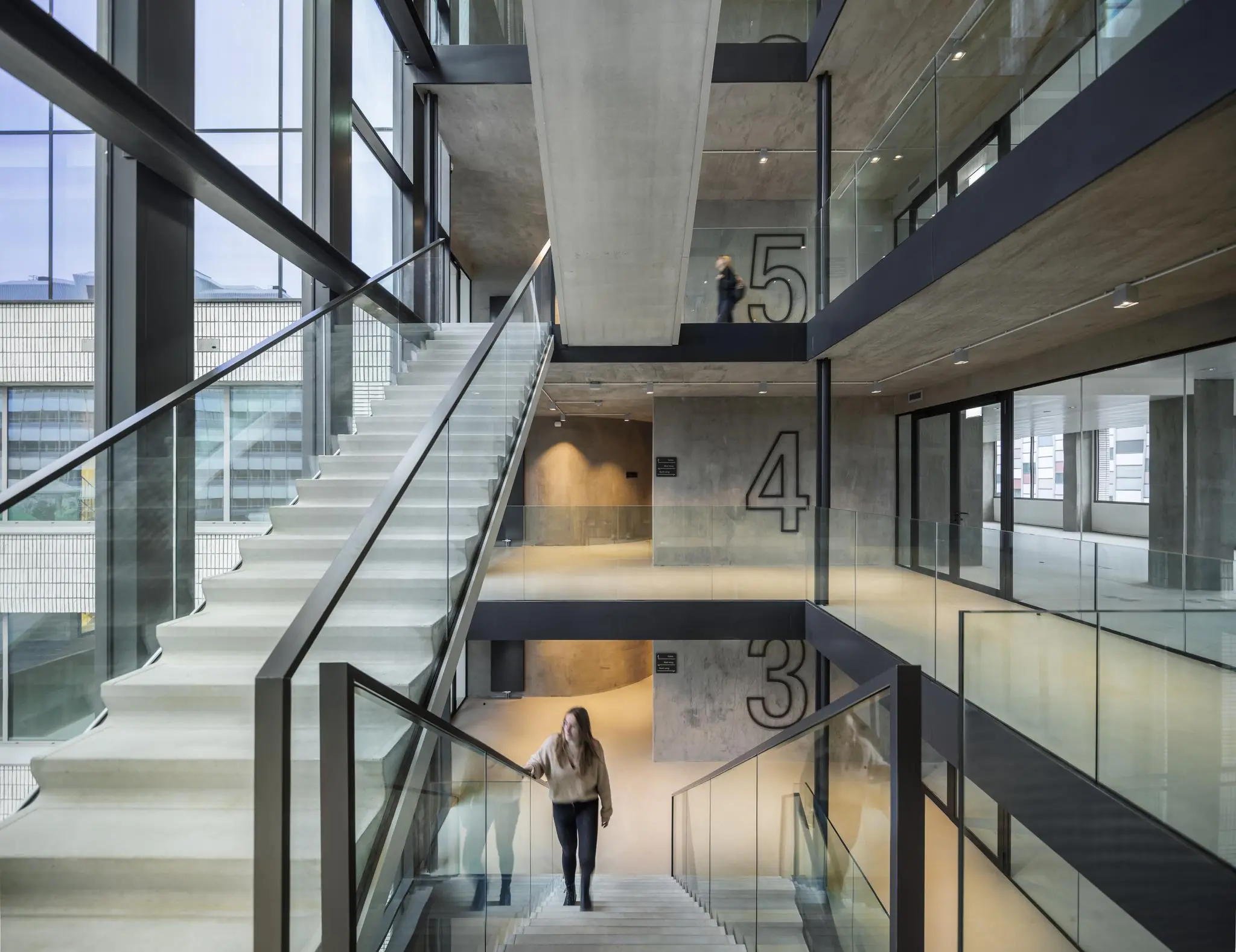 Moderne betonnen trappenhal met glazen balustrades in het gebouw aan de Catharijnesingel, met zicht op meerdere verdiepingen.