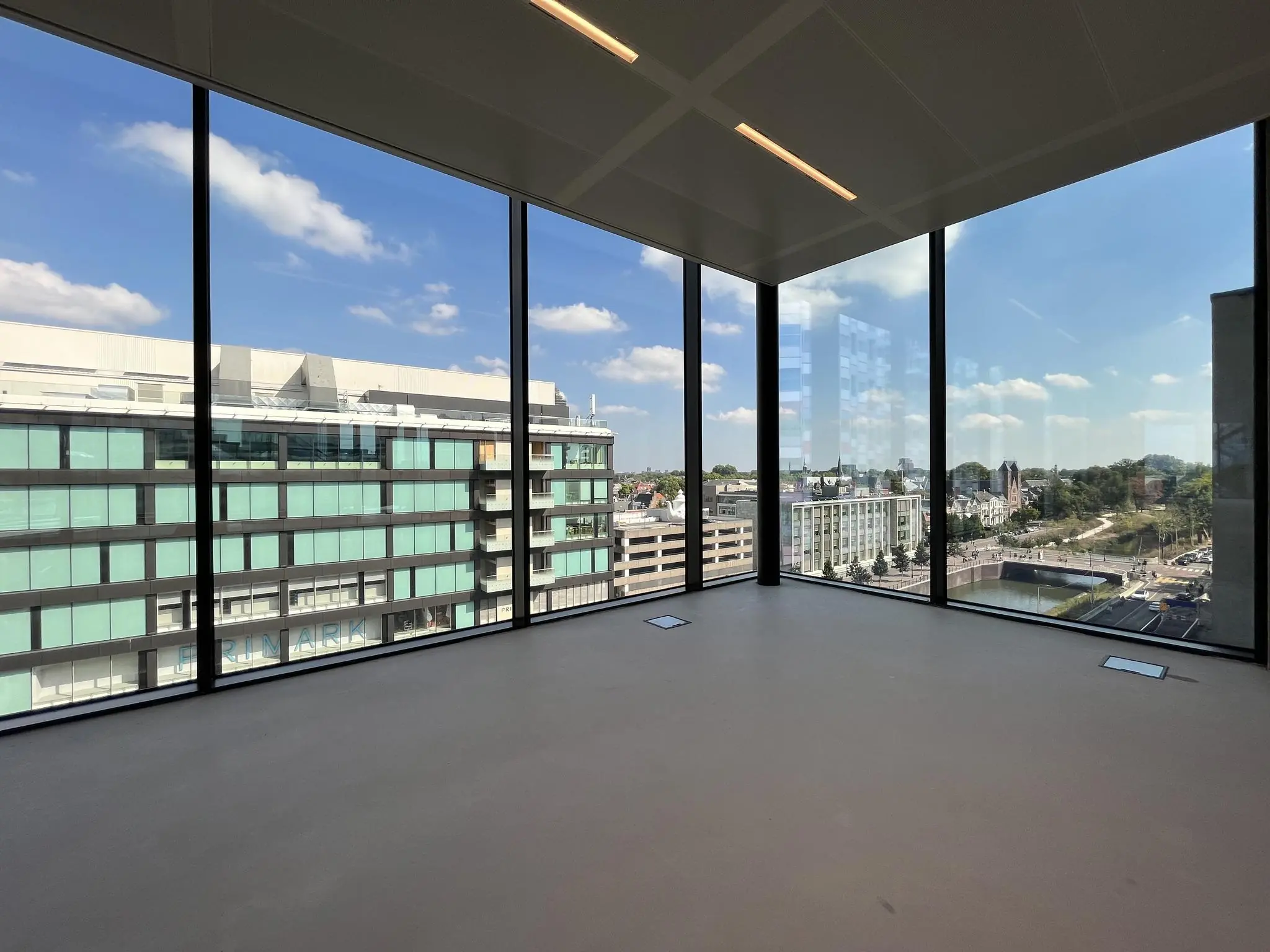 Uitzicht vanuit een modern, leeg hoekkantoor op de Catharijnesingel en omliggende gebouwen in Utrecht.
