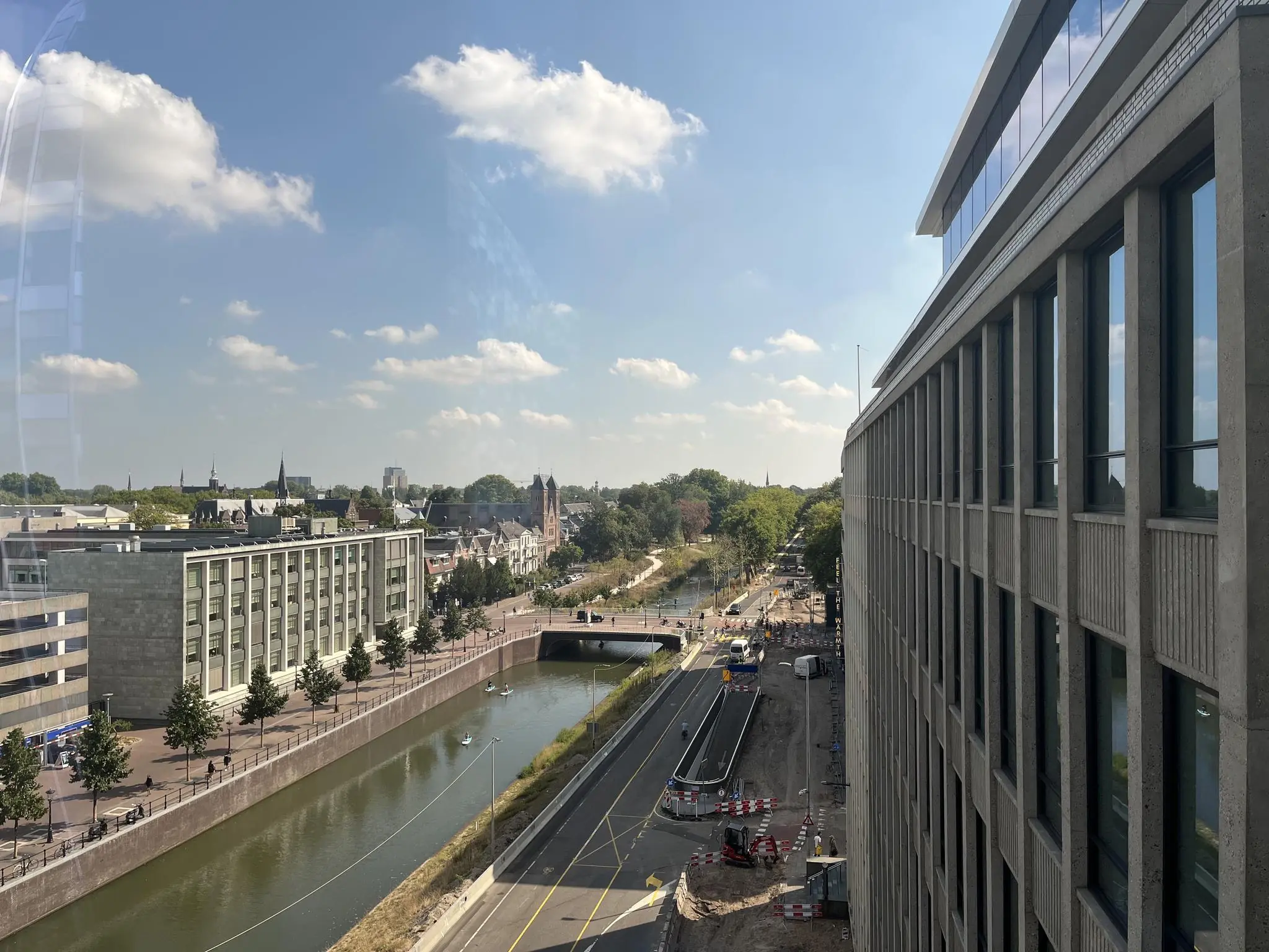 Uitzicht op de Catharijnesingel in Utrecht met water, gebouwen en een tramspoor onder een blauwe lucht.