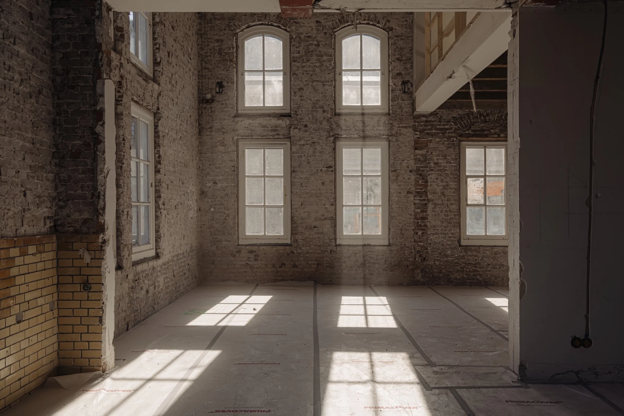 Lichte, lege ruimte aan de Leidseweg met bakstenen muren, hoge ramen en zichtbare renovatiewerkzaamheden.