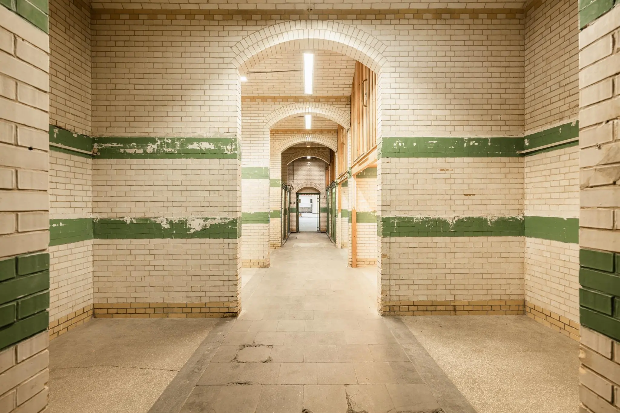 Geverfde gang met witgele bakstenen en groene accenten in een oud gebouw aan de Leidseweg.