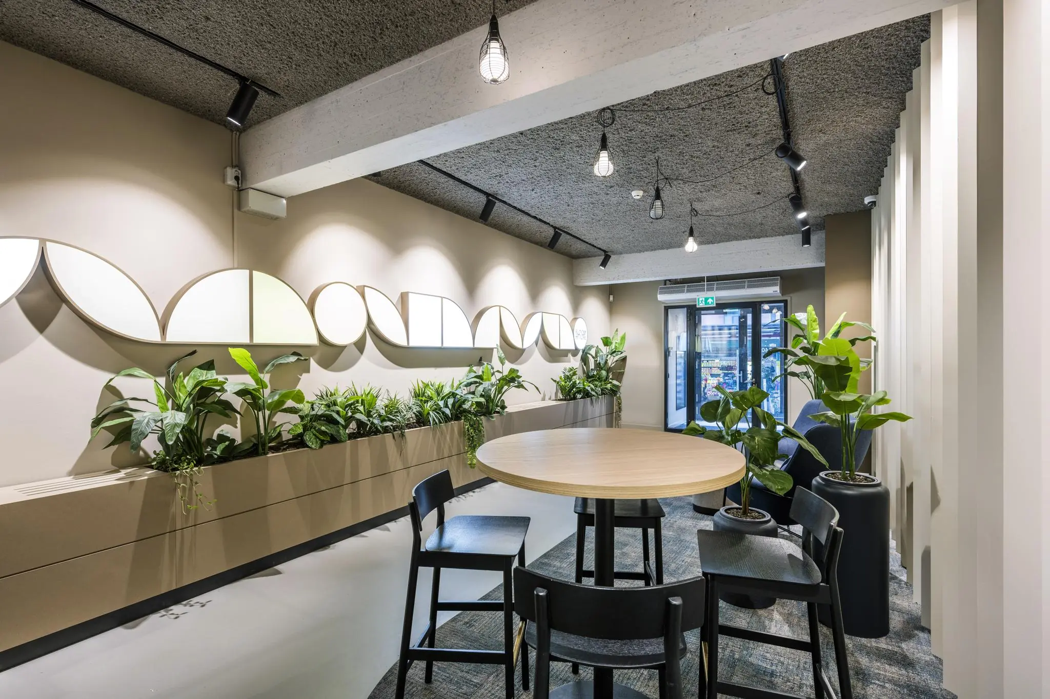 Moderne wachtruimte met ronde tafel, zwarte stoelen, veel groene planten en wanddecoratie in het gebouw aan de Singel.