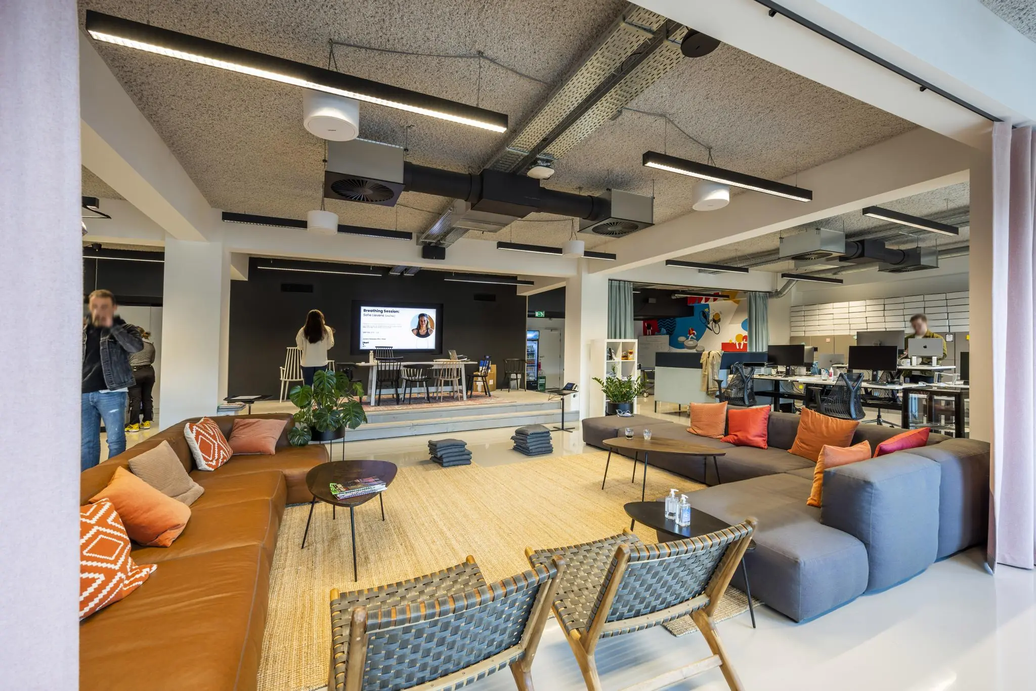 Moderne kantoorruimte aan de Singel met een loungehoek, podium en werkplekken in open indeling.