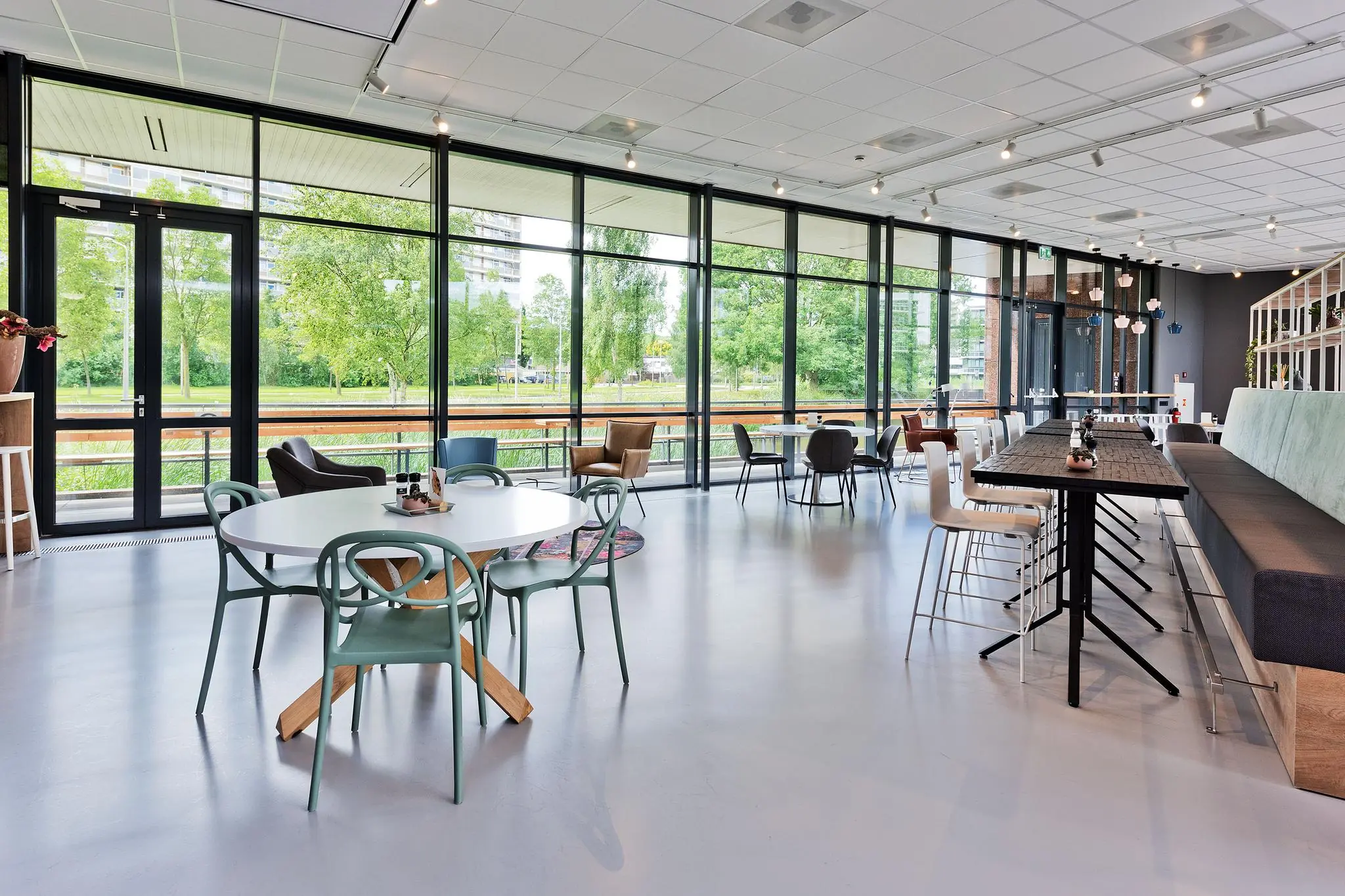 Moderne en licht ingerichte kantineruimte aan de Prof. W.H. Keesomlaan met grote ramen en uitzicht op groen.