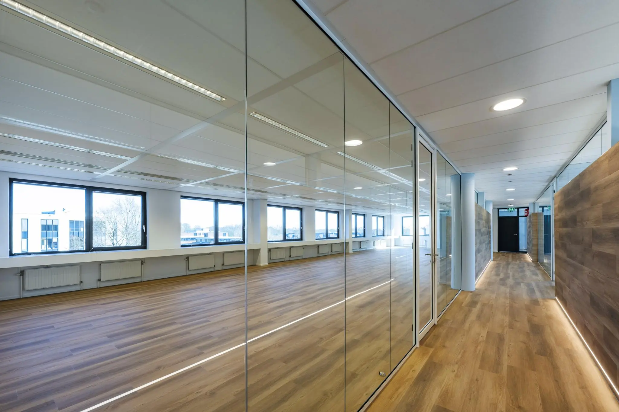 Moderne kantoorruimte aan de Prof. W.H. Keesomlaan met glazen wanden en houten vloeren.
