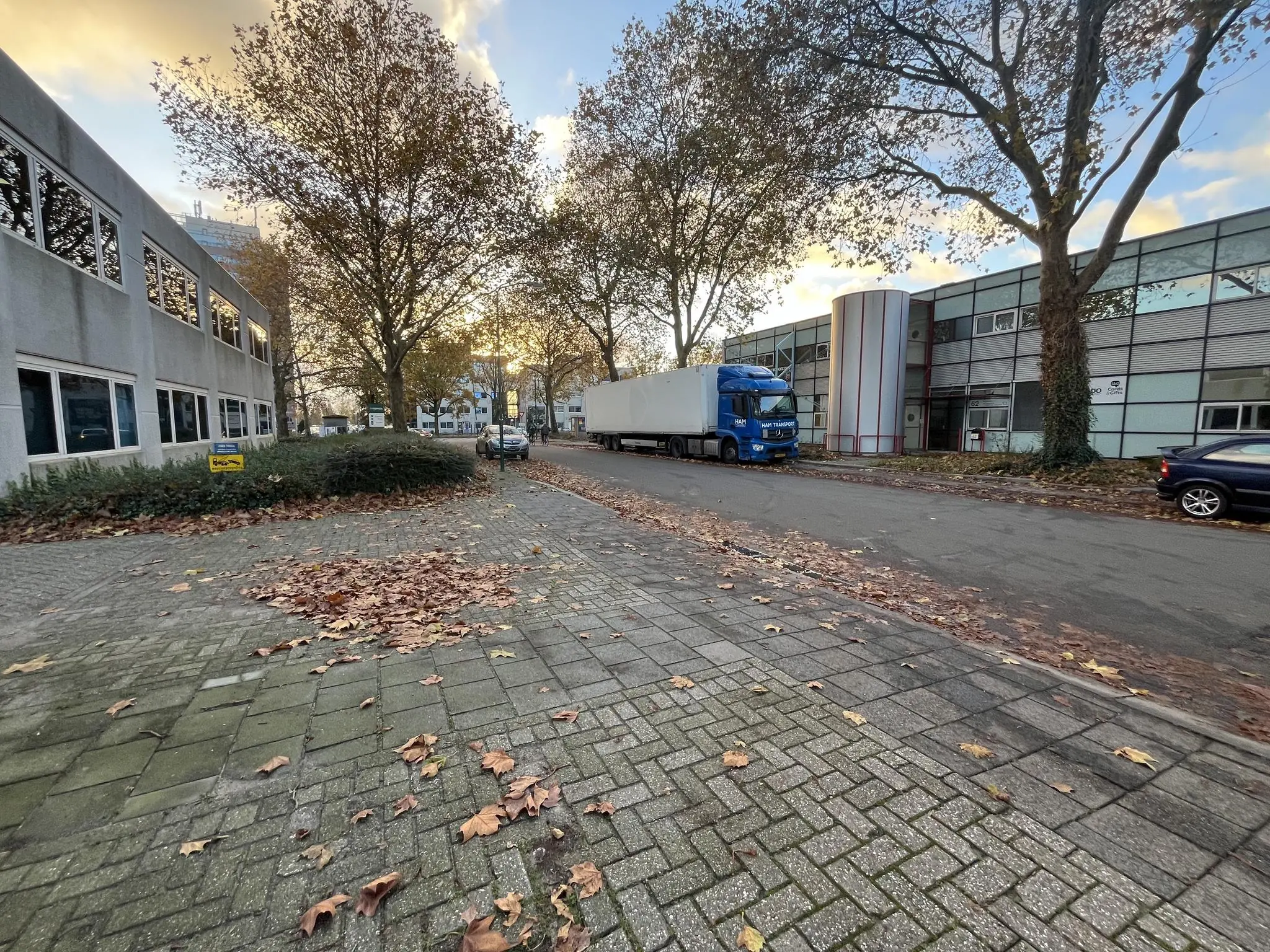 Een rustige straat op een bedrijventerrein aan de Industrieweg met geparkeerde vrachtwagens en kantoorgebouwen in herfstige sfeer.