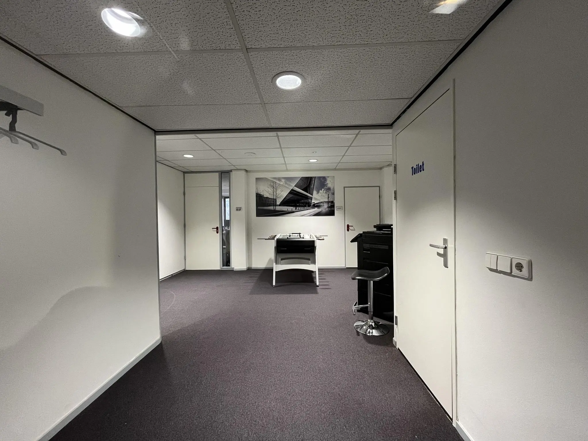 Zakelijke kantoorhal met een printer, een toiletdeur en een zwart-wit foto aan de muur aan de Industrieweg.