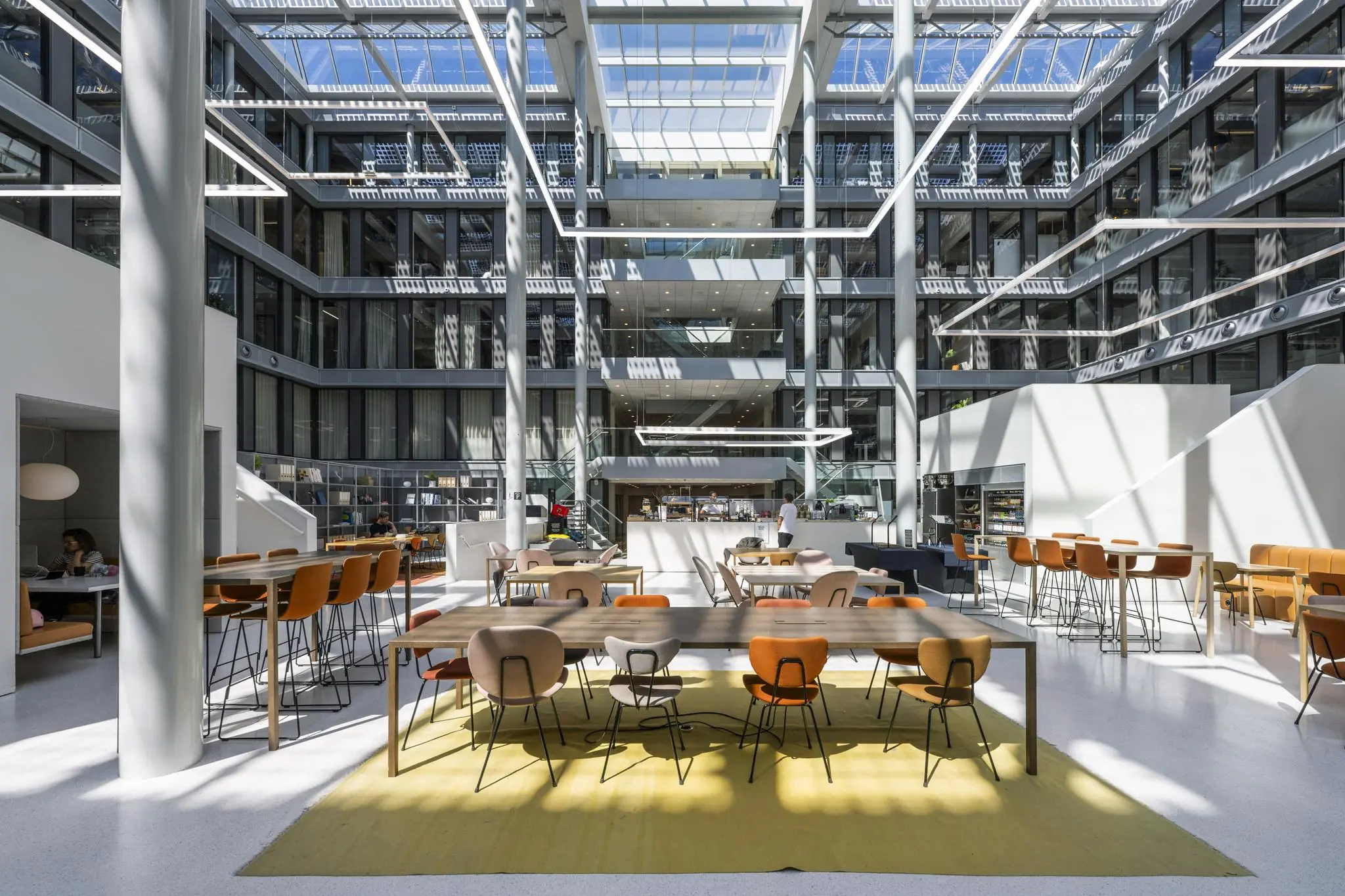 Moderne, lichtovergoten kantoorlobby aan de Mr. Treublaan met zitgelegenheden en een open lunchruimte.