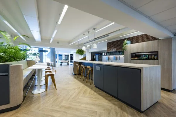 Moderne kantoorruimte aan de Mr. Treublaan met een open keuken, zithoek en speeltafel in een lichte en groene inrichting.