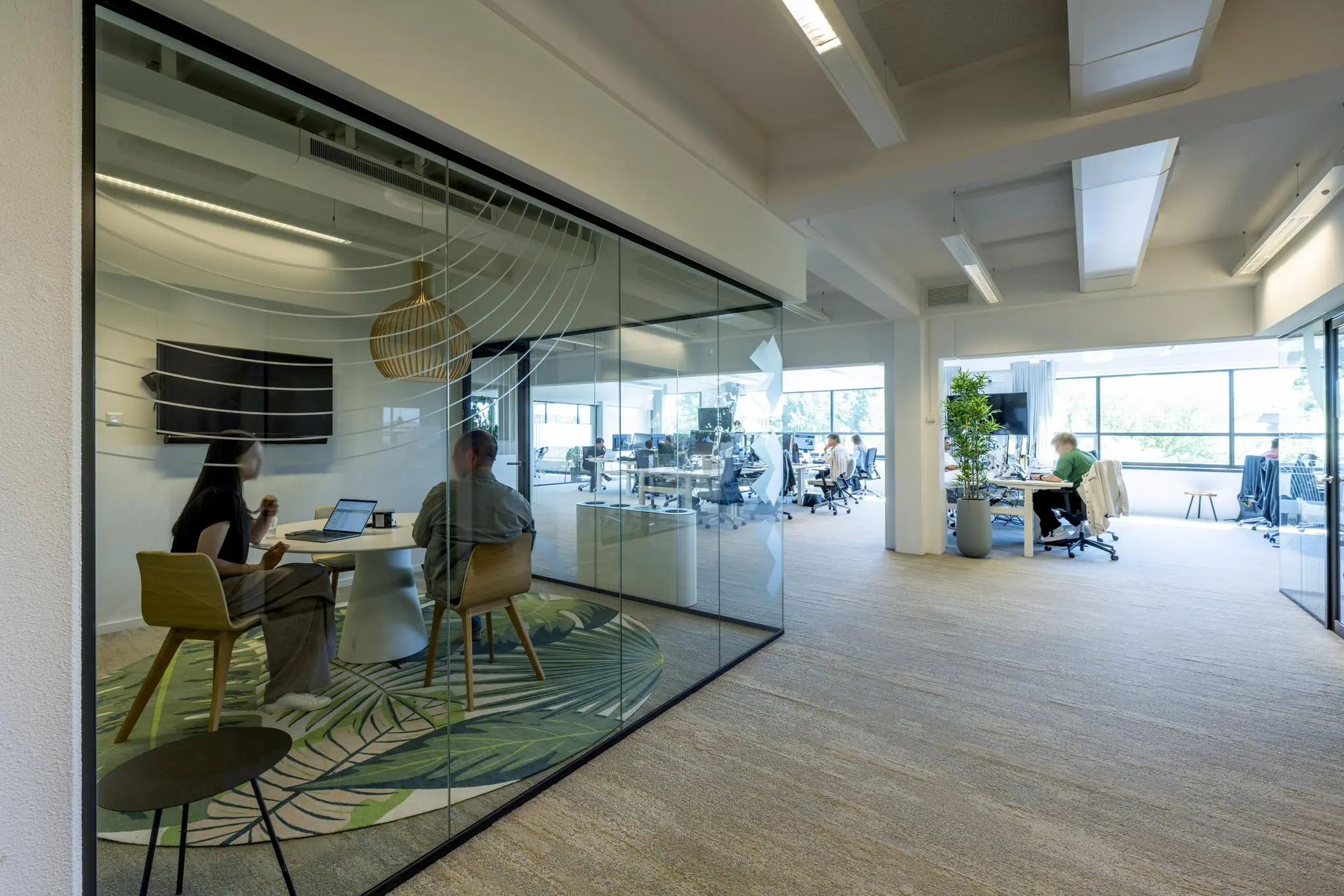 Modern kantoorinterieur aan de Mr. Treublaan met glazen vergaderruimte en open werkplekken.