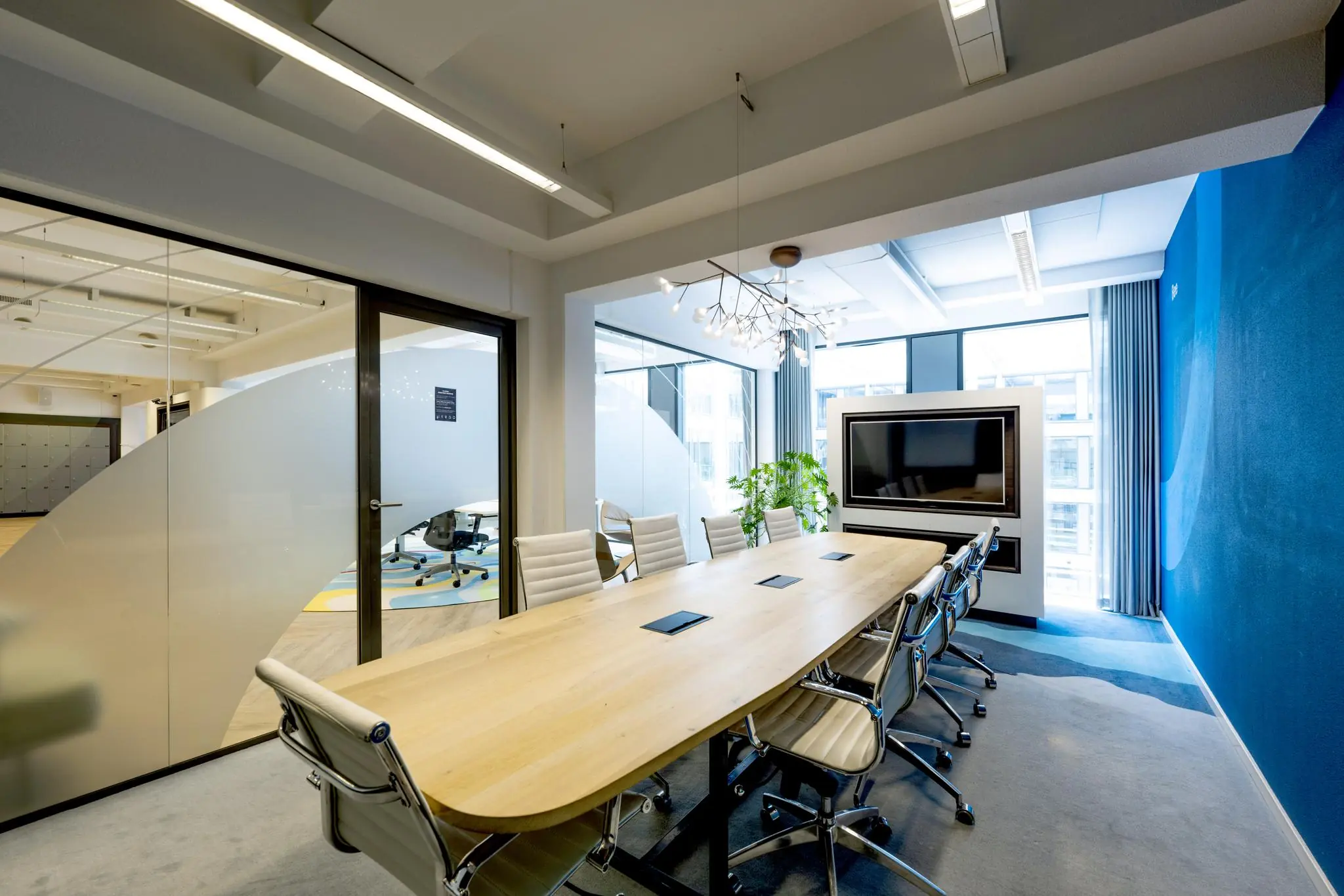 Moderne vergaderruimte aan de Mr. Treublaan met lange houten tafel, ergonomische stoelen en groot presentatiescherm.