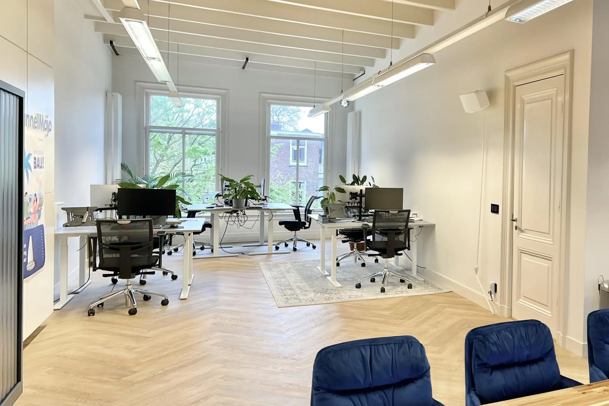 Modern kantoorinterieur aan de Paulus Potterstraat met bureaus, computerschermen, planten en grote ramen.