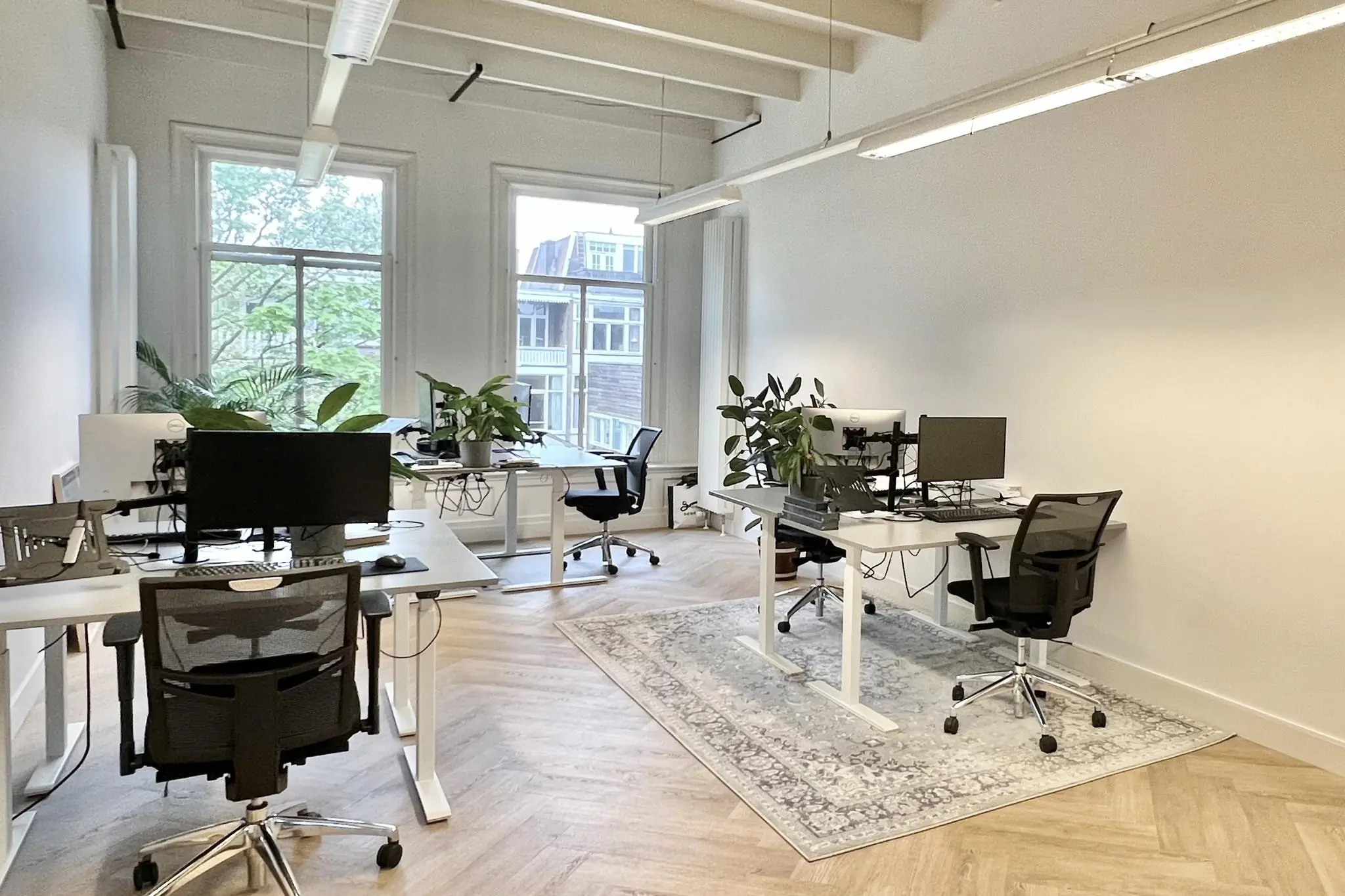 Modern en licht kantoor aan de Paulus Potterstraat met bureaus, bureaustoelen, planten en computers.