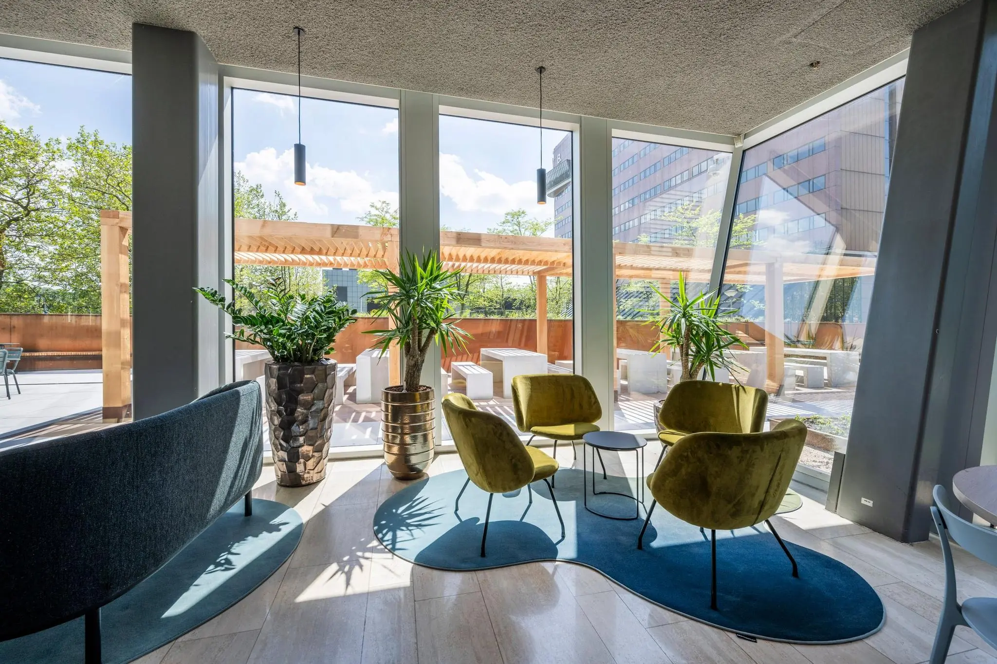 Moderne loungehoek met groene stoelen, planten en uitzicht op een terras aan de David Ricardostraat.