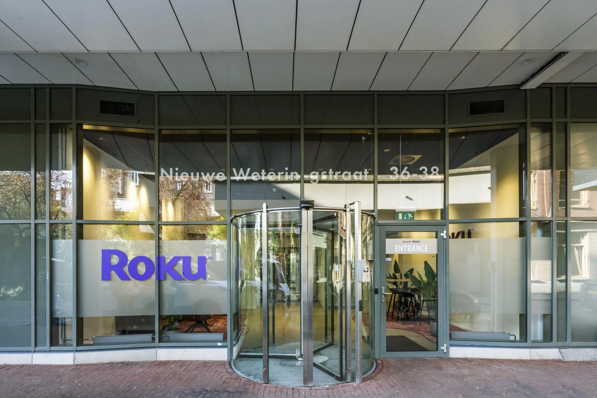 Ingang van het Roku-kantoor aan de Nieuwe Weteringstraat 36-38 met een draaiende glazen deur en bedrijfslogo op het raam.