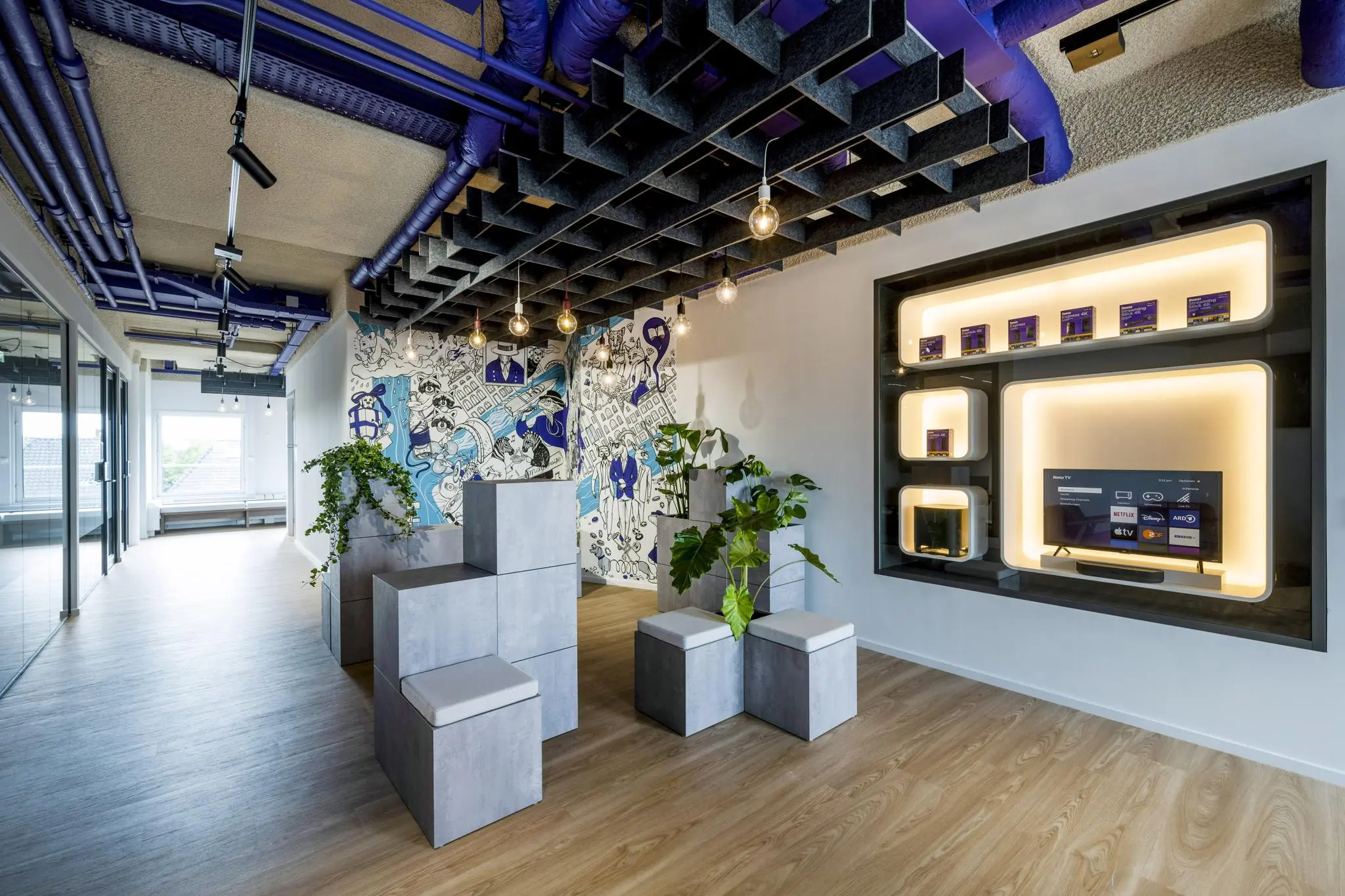 Modern ingericht kantoorinterieur aan de Vijzelgracht met creatieve muurschildering, designmeubilair en verlichte productpresentatie.