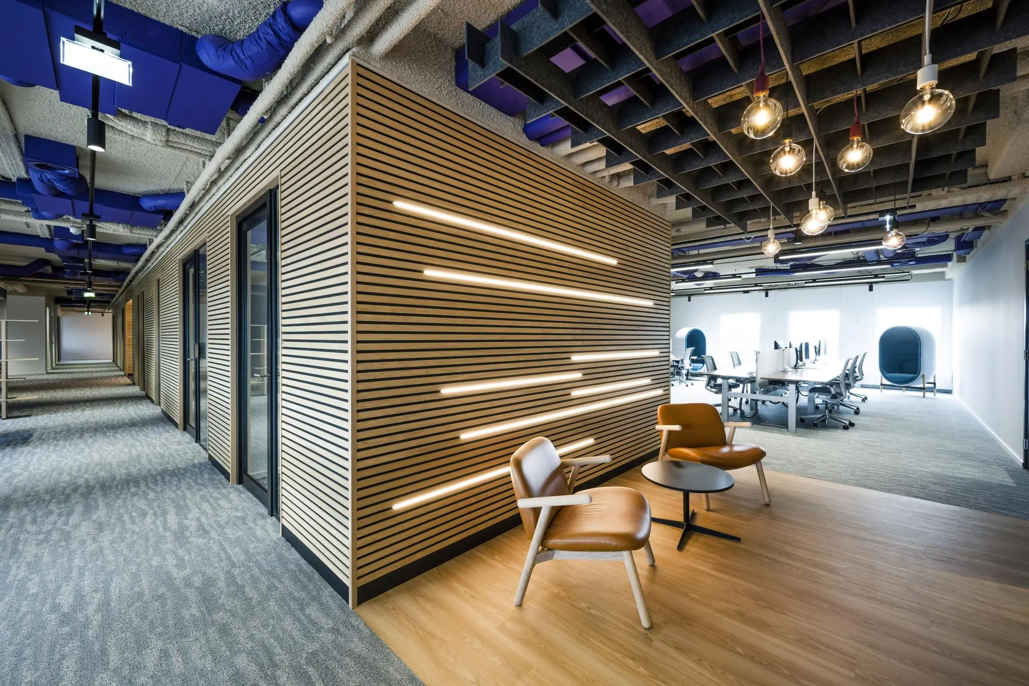 Modern kantoorinterieur aan de Vijzelgracht met houten wandbekleding, designstoelen en open werkruimte.