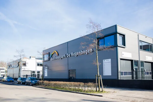Bedrijfspand aan de Laan van 's-Gravenmade met opschrift "Businesspark De Regenboog" op een zonnige dag.