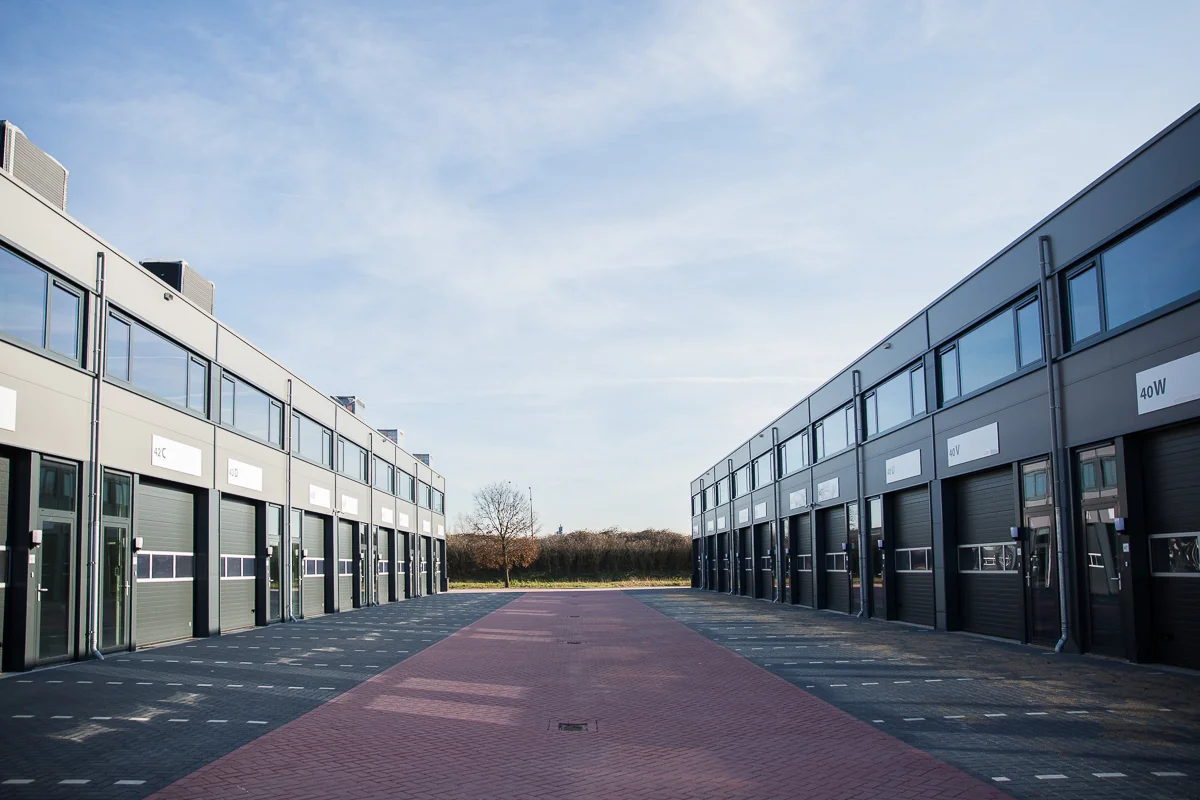 Moderne bedrijfsunits aan de Laan van S-Gravenmade met zwarte en grijze gevels en grote garagedeuren.