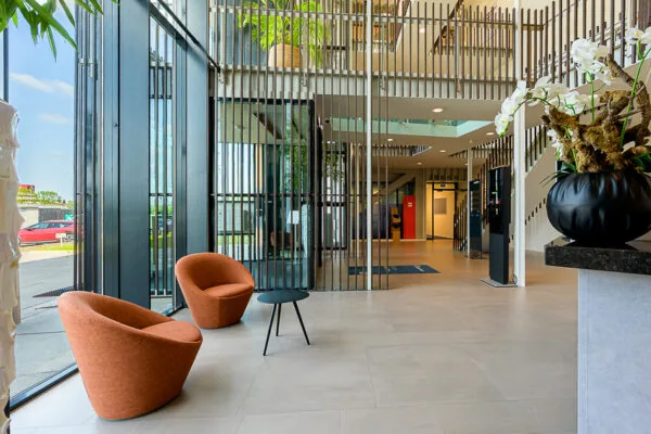 Modern office lobby at Laan van Barcelona with large windows, contemporary furniture, and vertical metal accents.