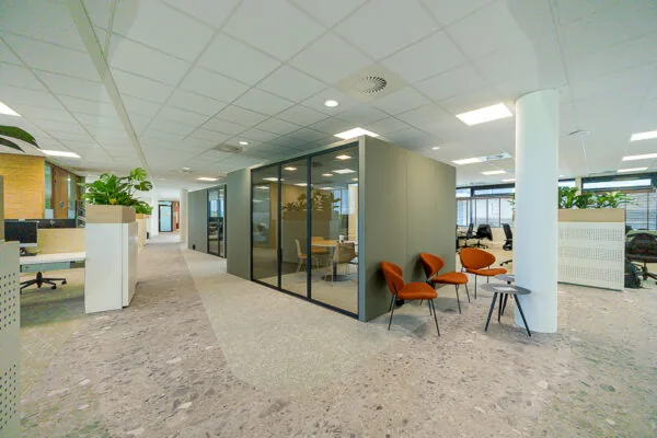 Modern office interior on Laan van Barcelona with glass meeting room, open workspaces, and seating area.