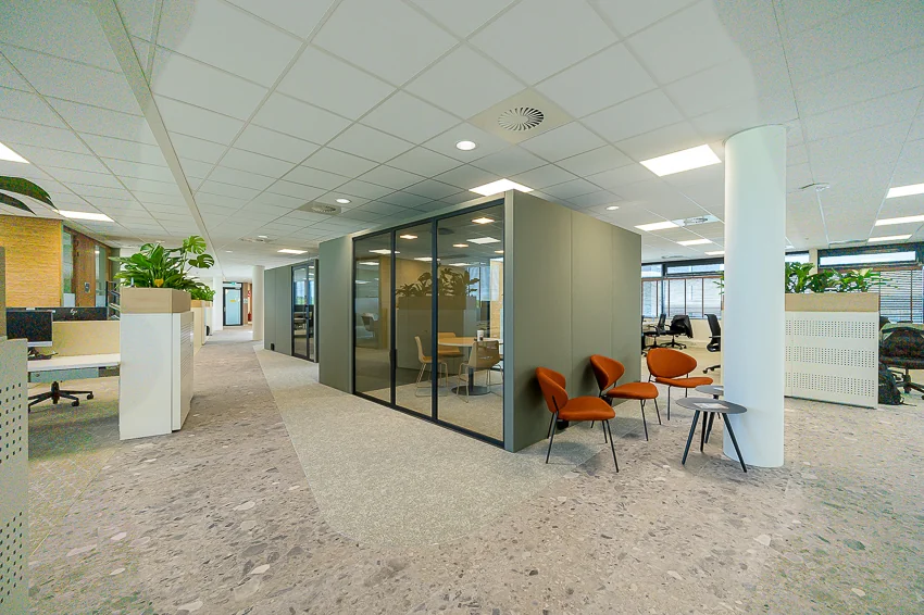 Modern office interior on Laan van Barcelona with glass meeting room, open workspaces, and seating area.