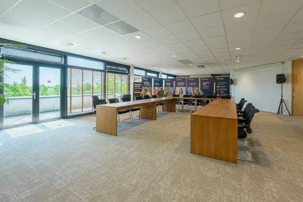 Modern conference room at Laan van Barcelona with U-shaped wooden tables, chairs, and promotional banners.