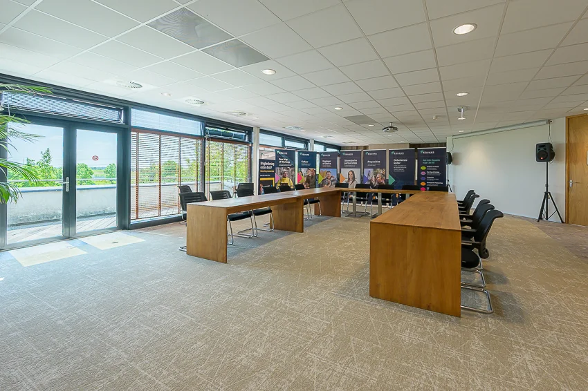Modern conference room at Laan van Barcelona with U-shaped wooden tables, chairs, and promotional banners.