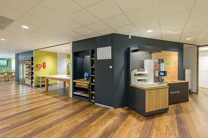 Modern self-service food and beverage corner at Laan van Barcelona with wooden flooring and minimalist design.