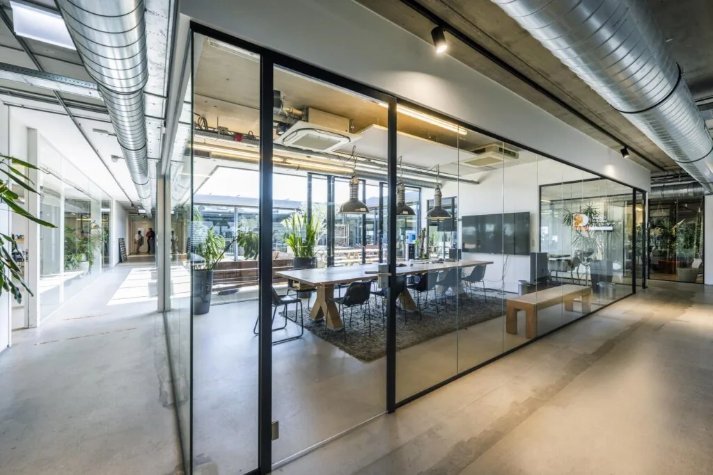 Moderne vergaderruimte met glazen wanden aan de Johan van Hasseltweg in een licht en industrieel kantoorinterieur.