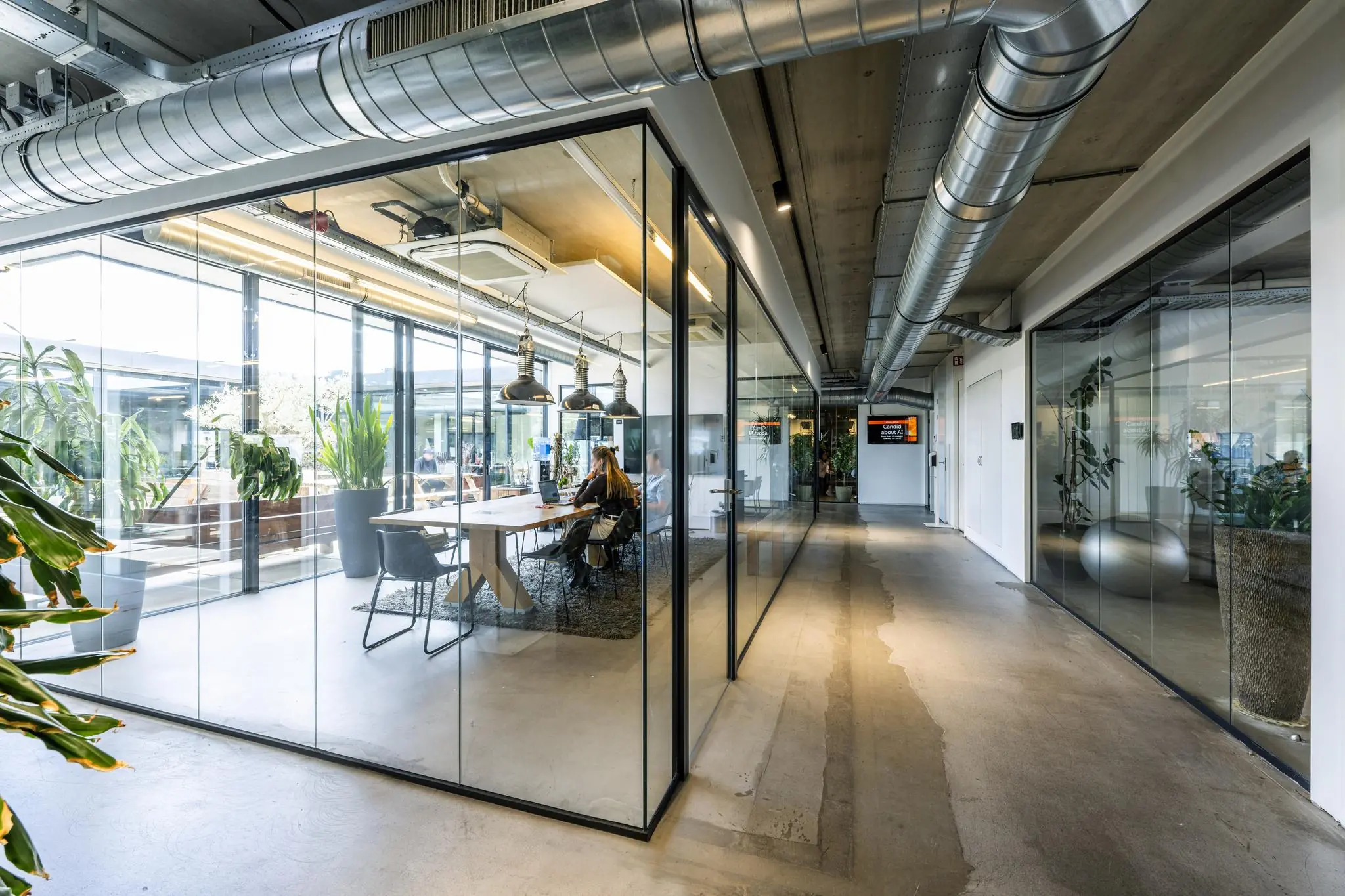 Moderne kantoorruimte aan de Johan van Hasseltweg met glazen vergaderruimtes, industriële details en veel natuurlijk licht.