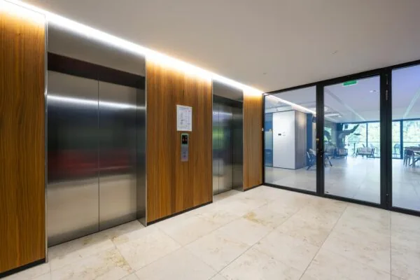 Moderne liftlobby met houten panelen en glazen deur in een kantoor aan de Gustav Mahlerlaan.