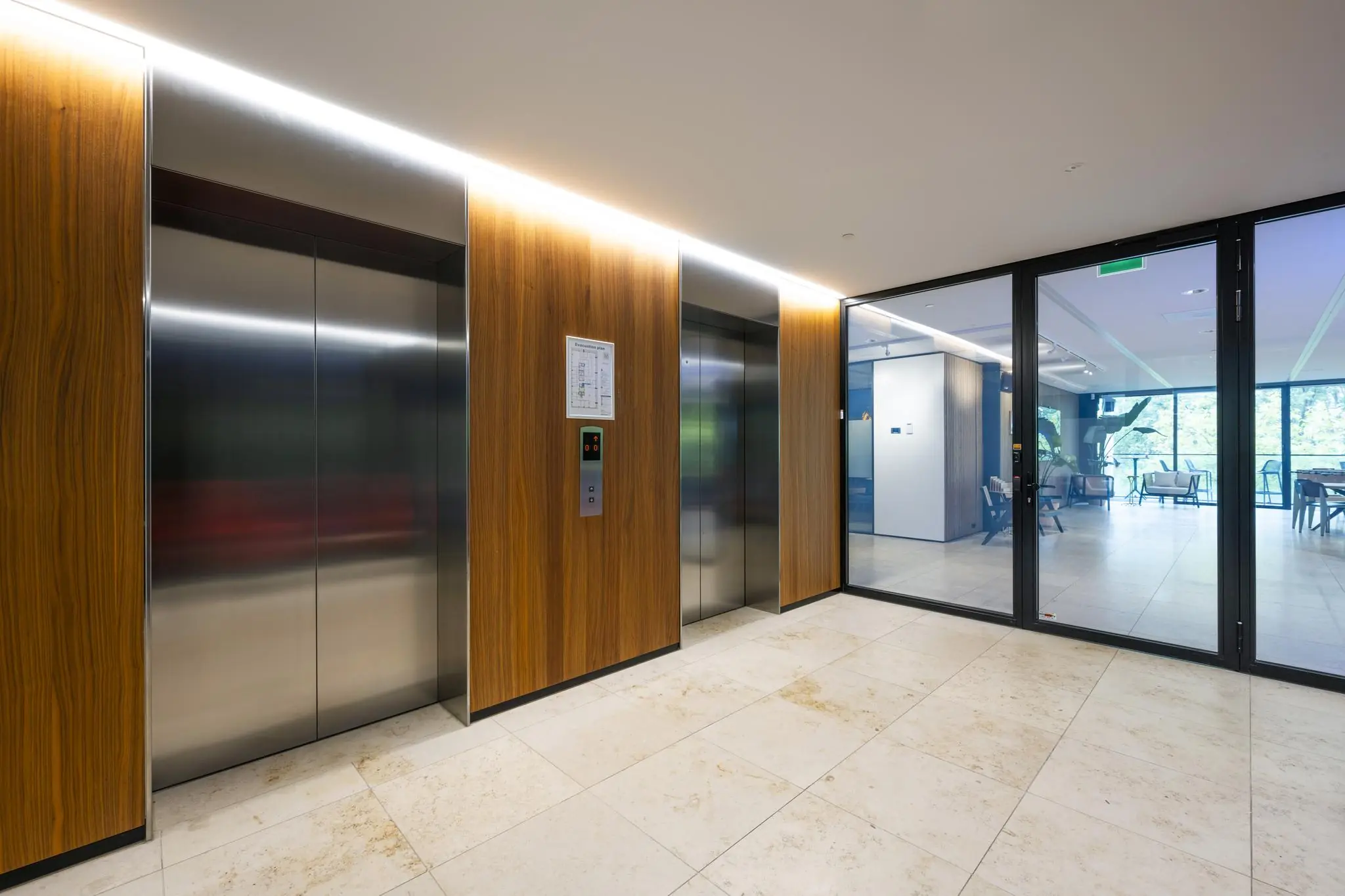 Moderne liftlobby met houten panelen en glazen deur in een kantoor aan de Gustav Mahlerlaan.