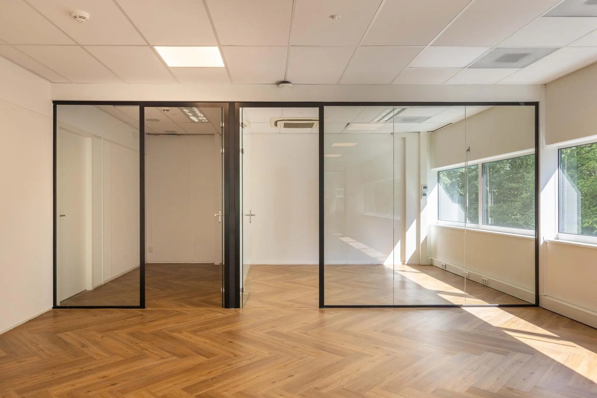 Licht en modern kantoorinterieur aan de Overschiestraat met glazen wanden en visgraat houten vloer.