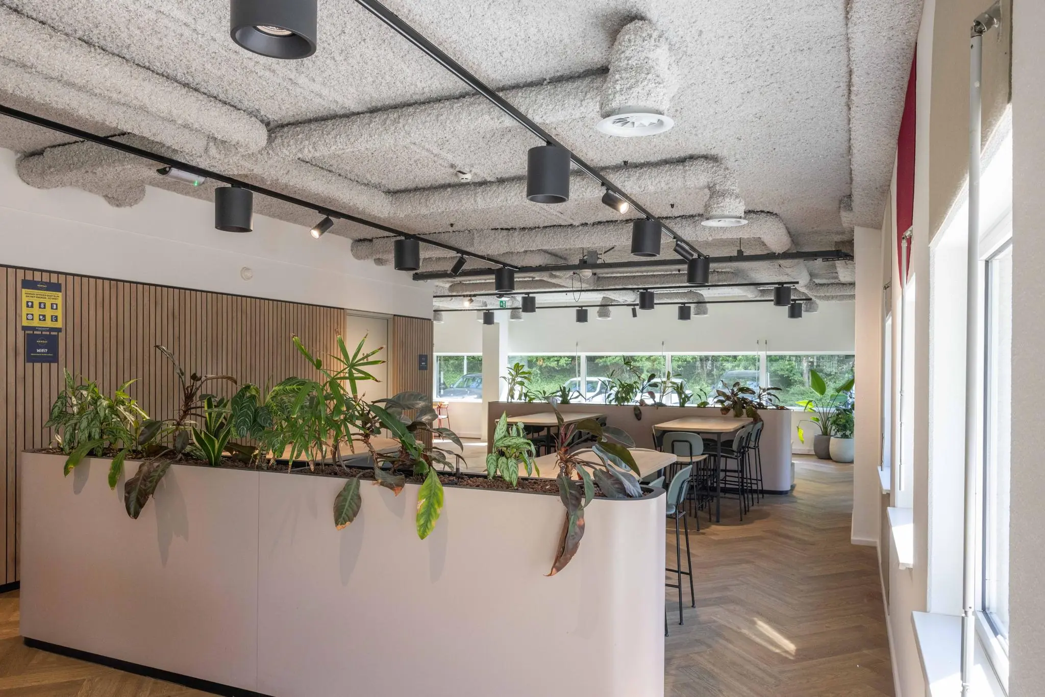 Moderne en lichte kantoorruimte aan de Overschiestraat met houten vloer, plantenbakken en zitgedeelte.
