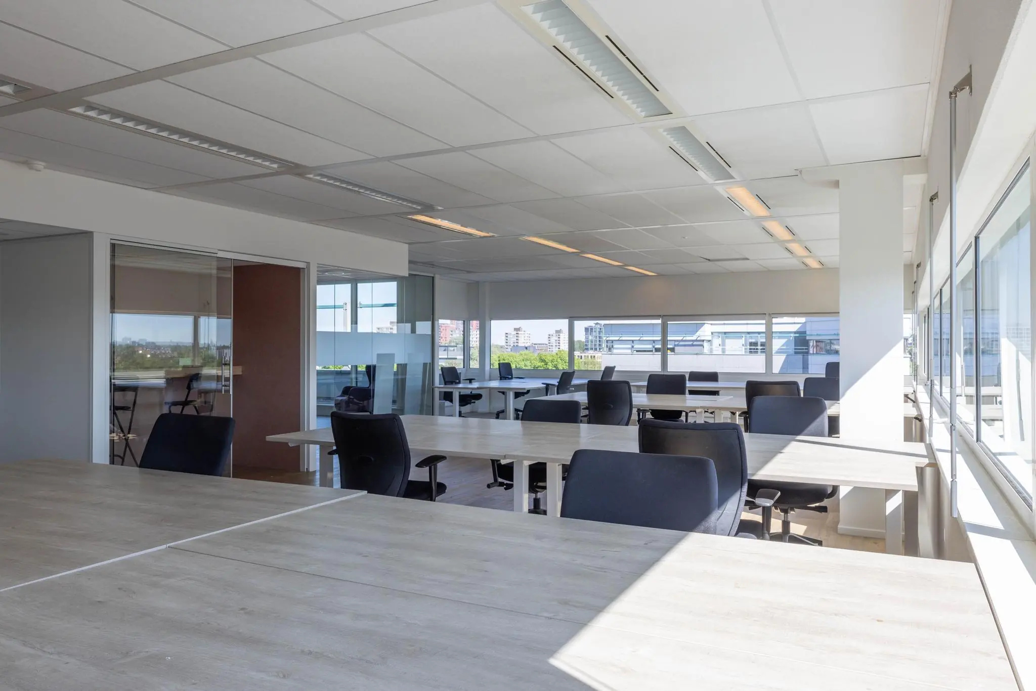 Licht en modern kantoorinterieur aan de Overschiestraat met meerdere bureaus en bureaustoelen.