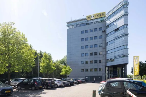 Kantoorgebouw aan de Overschiestraat met parkeerterrein en diverse geparkeerde auto's op een zonnige dag.