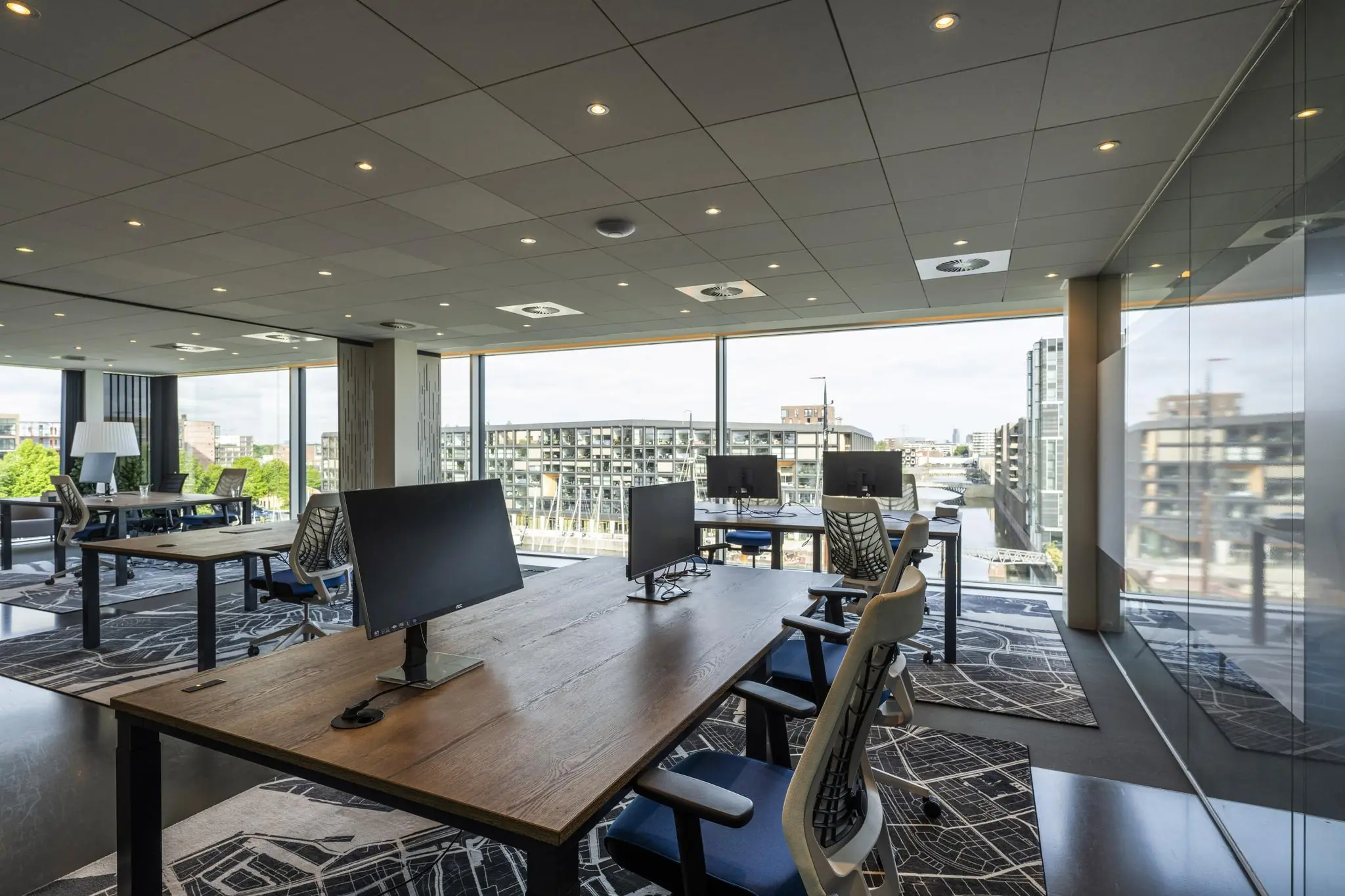 Modern kantoorinterieur aan de Krijn Taconiskade met grote ramen en uitzicht op omliggende gebouwen.