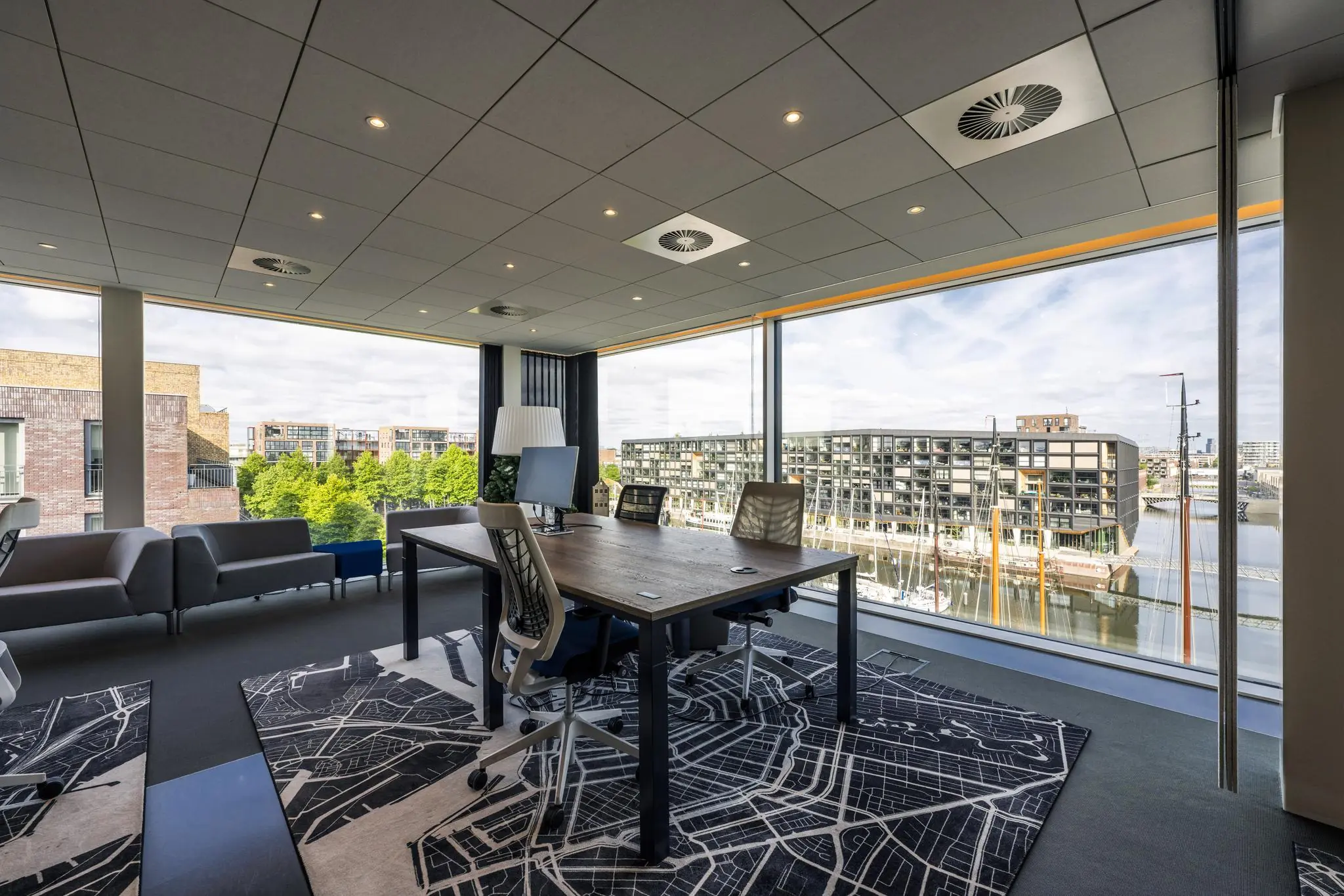 Modern kantoor met grote ramen en uitzicht op de Krijn Taconiskade en aangemeerde boten in een jachthaven.
