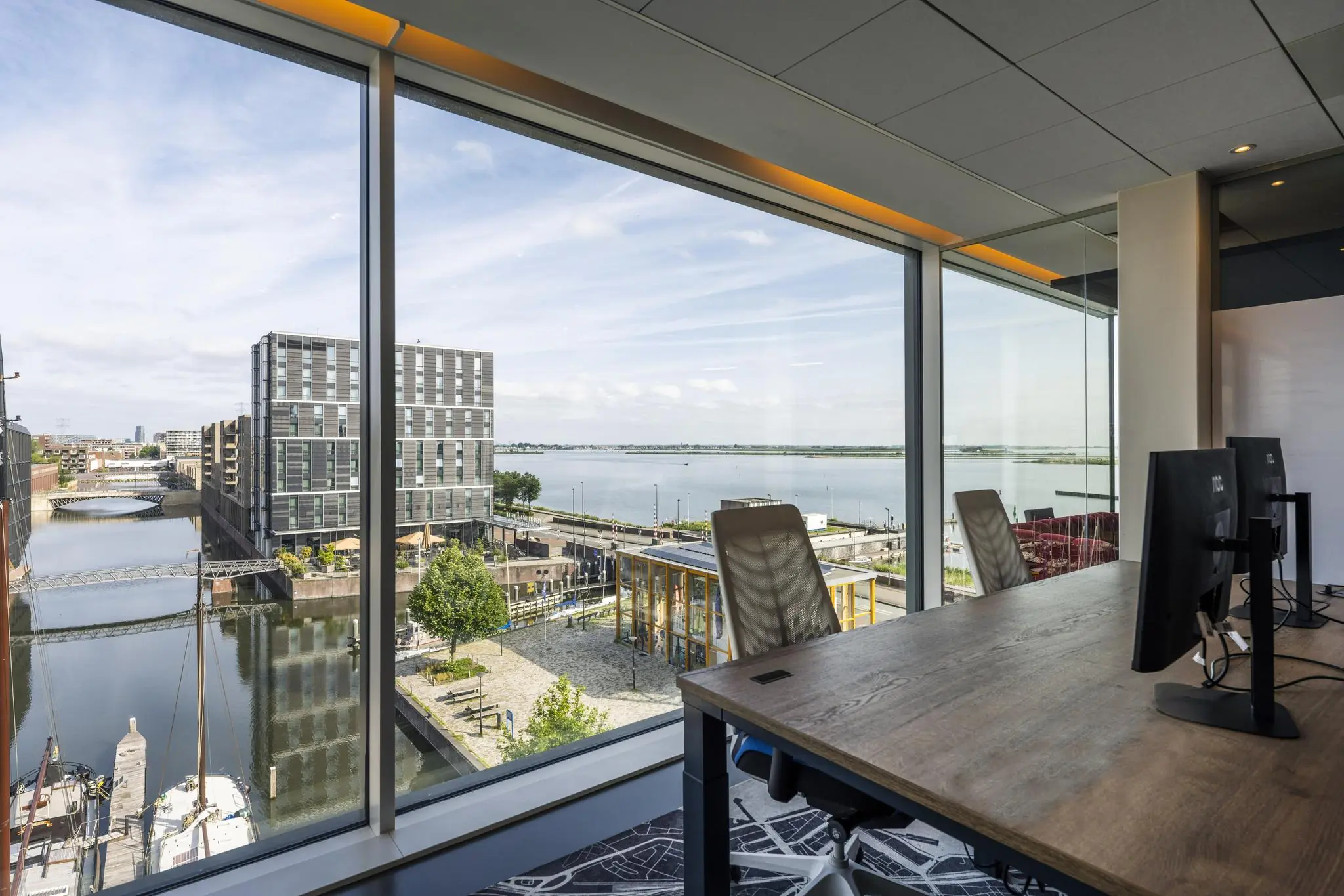 Kantoorruimte met uitzicht op de Krijn Taconiskade, moderne gebouwen en het IJmeer.
