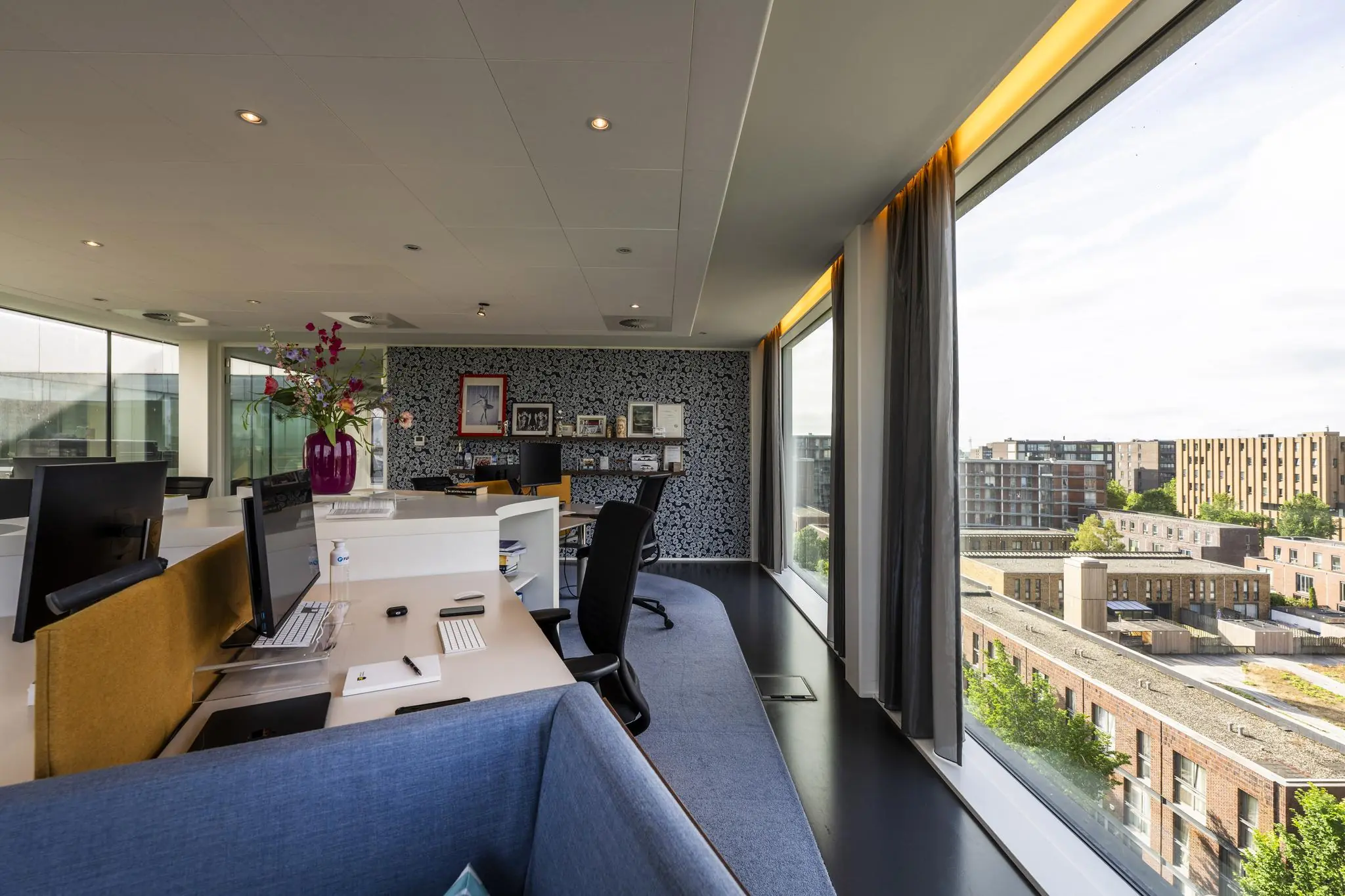 Modern kantoorinterieur aan de Krijn Taconiskade met grote ramen en uitzicht op woongebouwen.