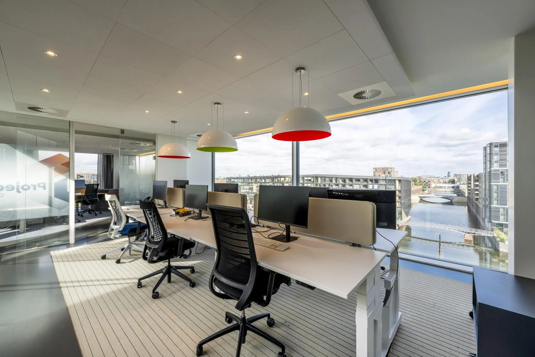 Modern ingericht kantoor aan de Krijn Taconiskade met werkplekken en uitzicht op het water en omliggende gebouwen.