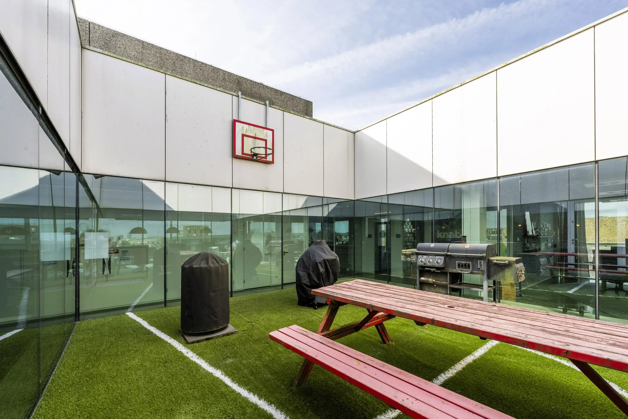 Dakterras aan de Krijn Taconiskade met kunstgras, picknicktafels, barbecue en basketbalnet.